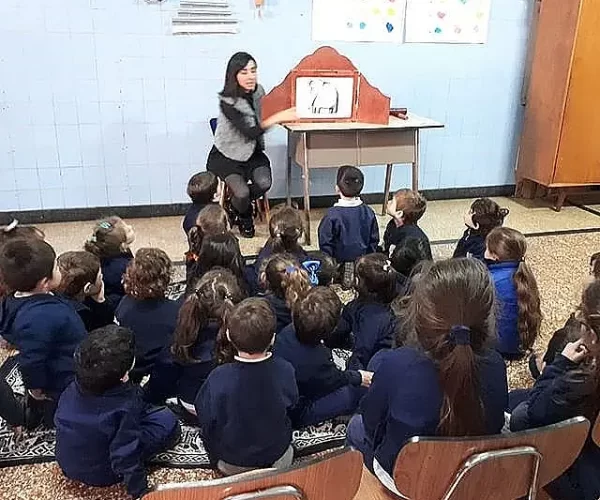 aula piso Niños de la primaria sentados en el piso recibiendo una clase especial. Prpuesta educativa del Colegio Mará Auxiliadora Boedo, Buenos Aires